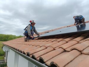 Ouvriers posant des panneaux photovoltaïques sur la toiture d'une maison